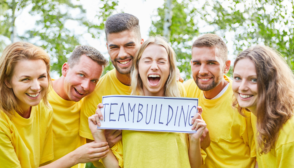 Lustige Firmenevents: Ein Team voller Lachen und Energie – bei diesem Teambuilding-Event im Freien zeigen die Kollegen ihre besten Grinsen und bringen den Teamgeist auf das nächste Level. In gelben T-Shirts und mit einem riesigen Teambuilding-Schild im Vordergrund wird dieses lustige Firmenevent garantiert zum Highlight des Jahres!