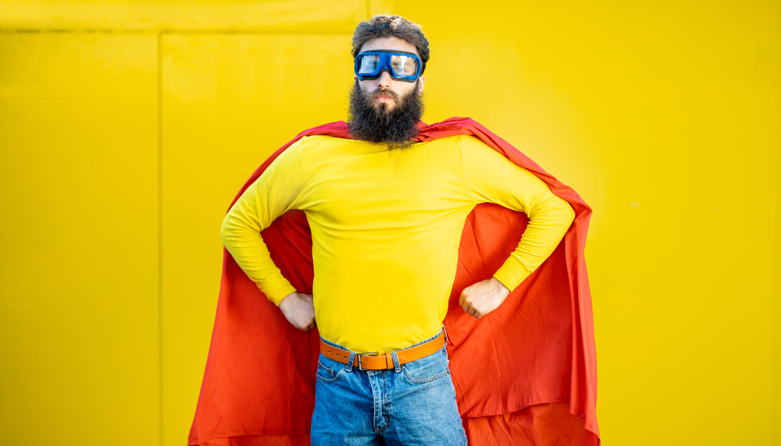 Ein Mann im ueberspitzten Superhelden-Look, der selbstironisch posiert – Darstellung davon, wie Humor macht attraktiv, wenn er selbstbewusst und spielerisch eingesetzt wird.