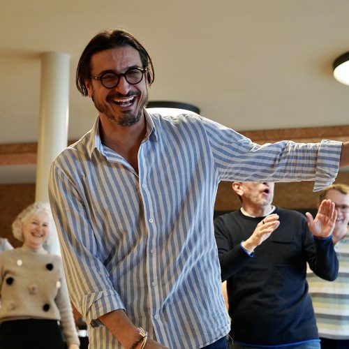 Coaching für Führungskräfte, Mann in weiss hellblau gestreiften Shirt mit Brille beim Ausführen der Coaching Übungen