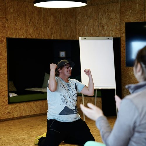 Mann in T Shirt und Trainerhosen, der CEO ist, jubelt beim Coaching für Führungskräfte Workshop